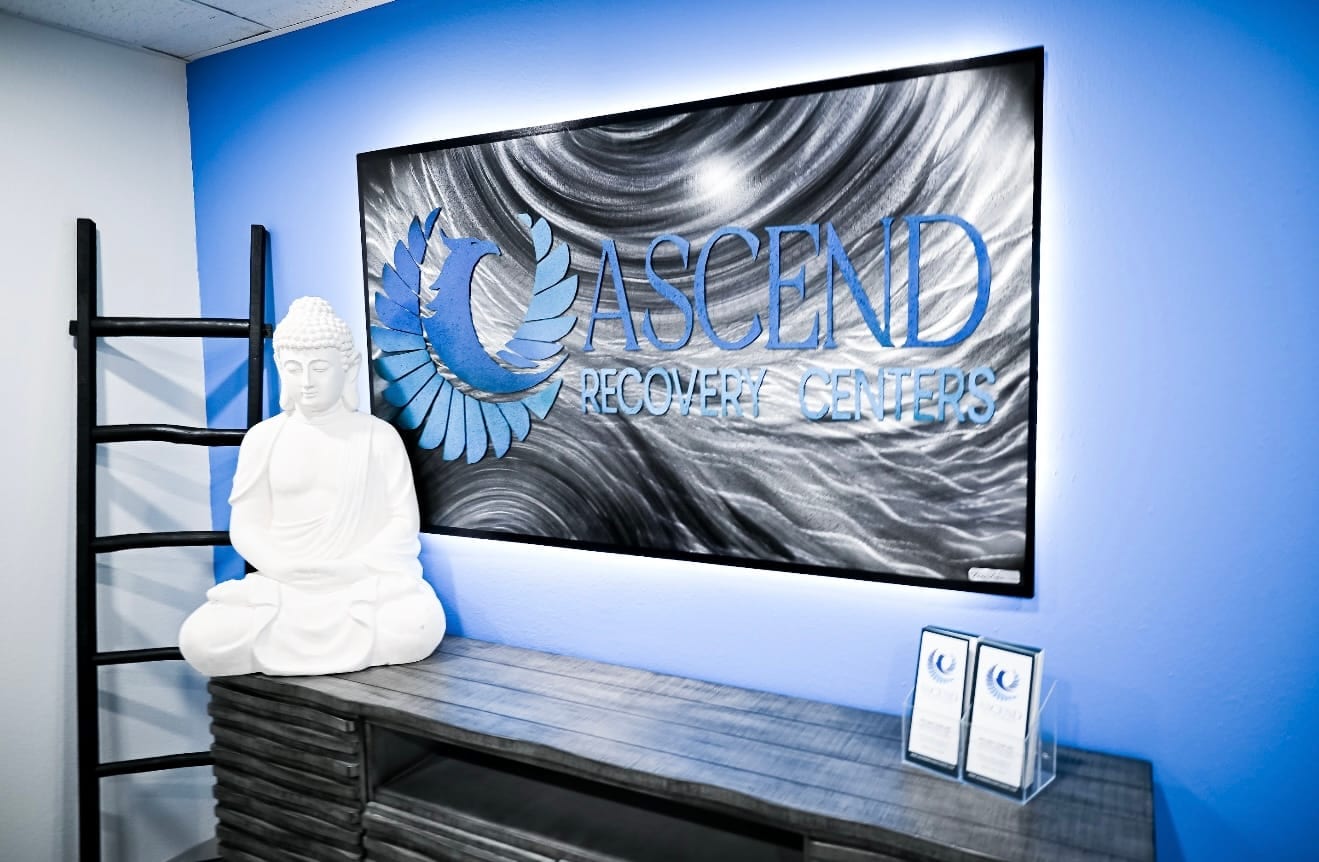 The Ascend Recovery Centers metal sign and a Buddha statue on a blue accent wall in the Albuquerque lobby